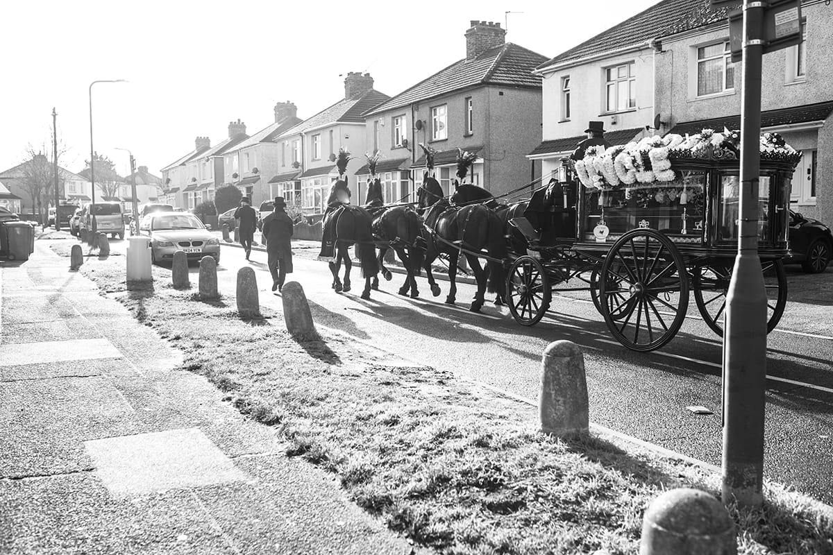 black and white photo of hearse and horses on street